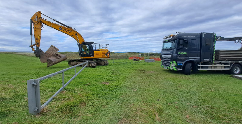 Digger and HGV in grassy field.